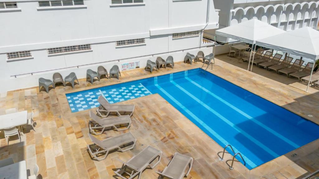 an overhead view of a large swimming pool with chairs and a table at Hotel Arhuaco Rodadero in Santa Marta