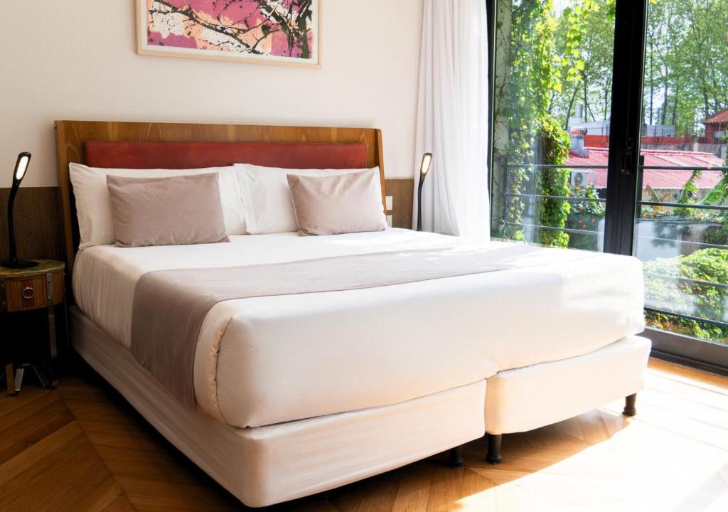 een wit bed in een kamer met een groot raam bij Hotel Palermitano by DOT Boutique in Buenos Aires