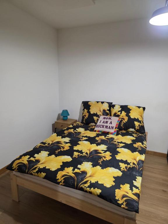 a bed with a black and yellow comforter and a pillow at Apartament klimatyczny in Piece