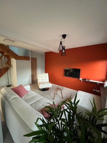 ein Wohnzimmer mit einem weißen Sofa und einem Fernseher in der Unterkunft Gite le Mamama, maison cosy au centre du village in Sommerau