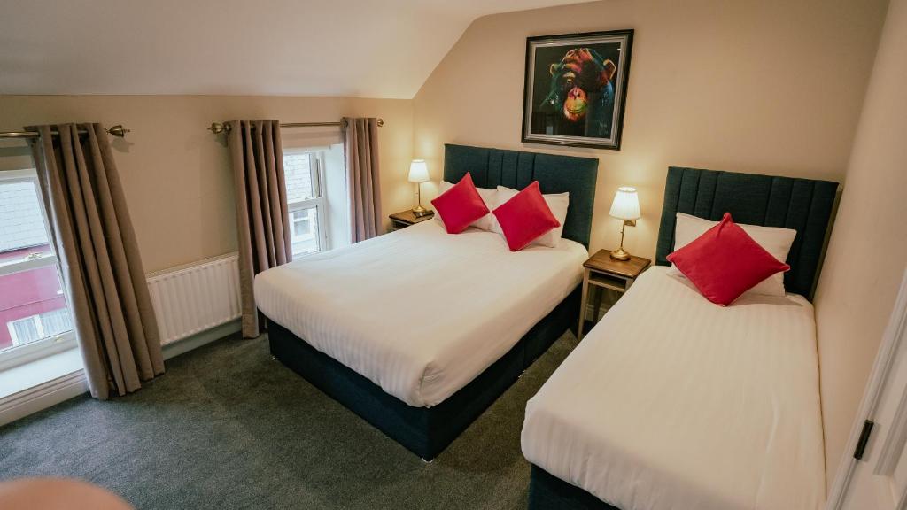two beds in a hotel room with red pillows at JUST B Townhouse in Dingle