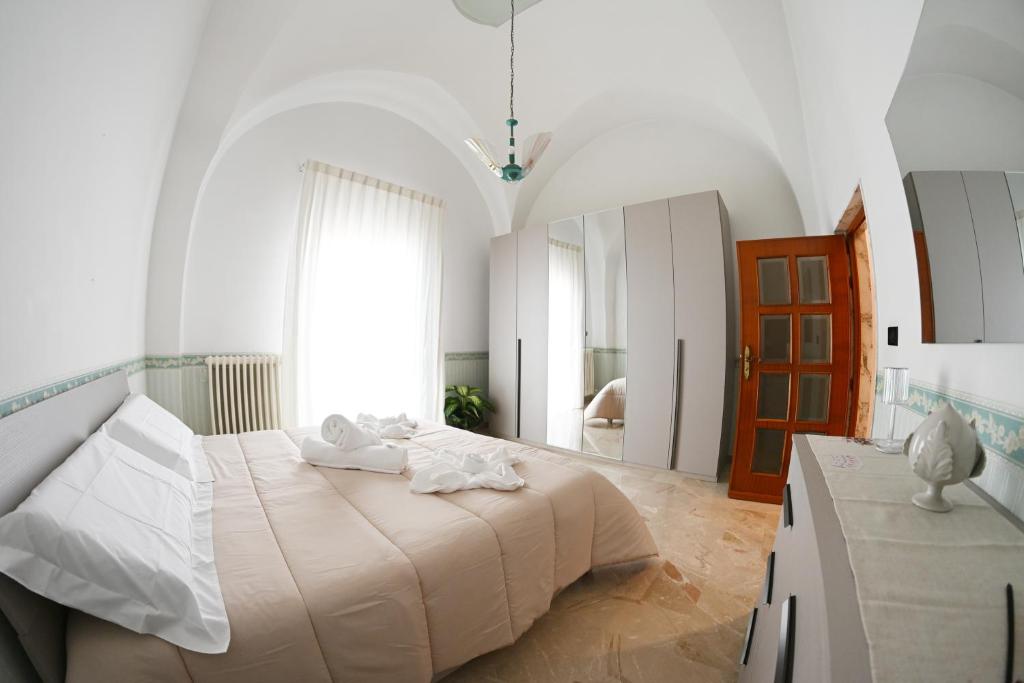 a white bedroom with a large bed and a window at A Casa di Nonna Nunzia - Centro di Gravina - 20min da Matera in Gravina in Puglia