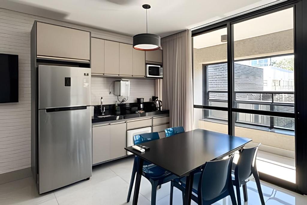 a kitchen with a table and chairs and a refrigerator at Studio Compacto com Design Clean no Vertigo in Campo Grande