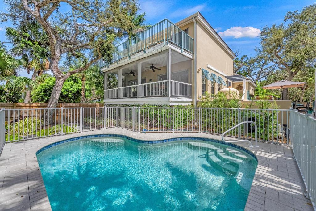 a house with a swimming pool in front of a fence at Hemingway House - 117 in Siesta Key