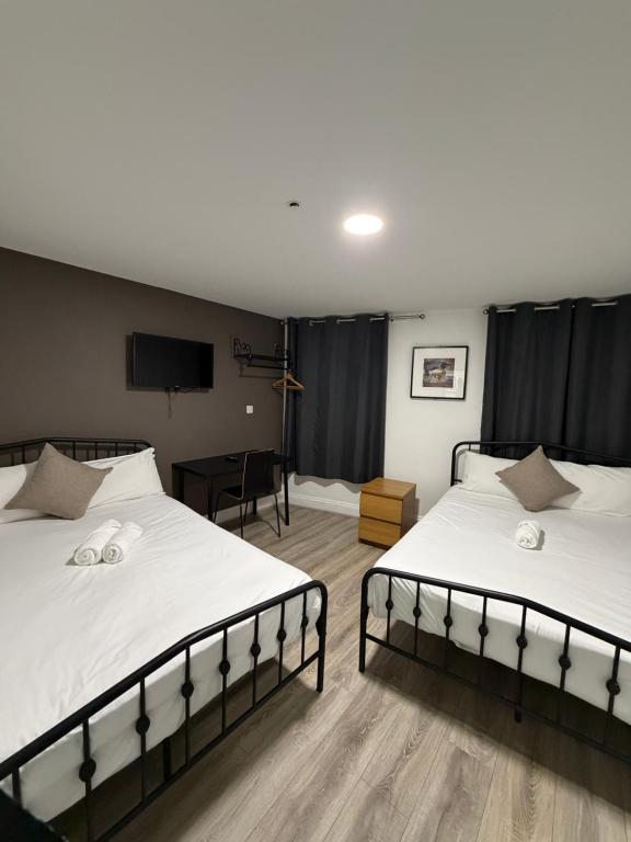 Un dormitorio con dos camas y un televisor. en TBH Hotel, en Barking