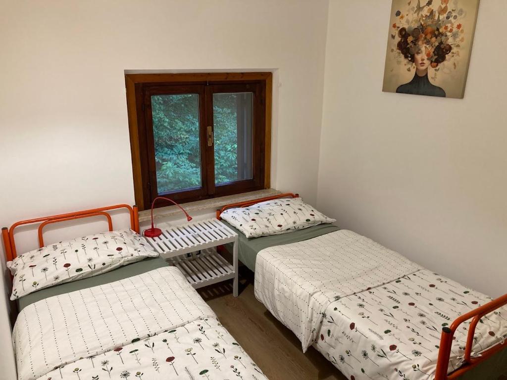 een kamer met twee eenpersoonsbedden en een raam bij L'Intermezzo in Venzone