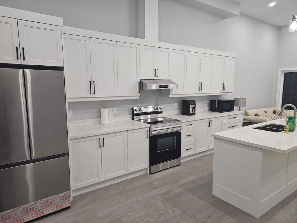 a kitchen with white cabinets and stainless steel appliances at Brand new custom 4BR house in Oshawa