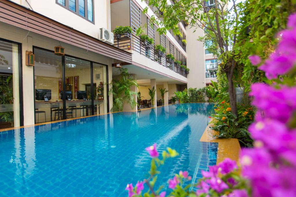 a swimming pool in the middle of a building with purple flowers at Chiang Mai Waroros Boutique Hotel in Chiang Mai