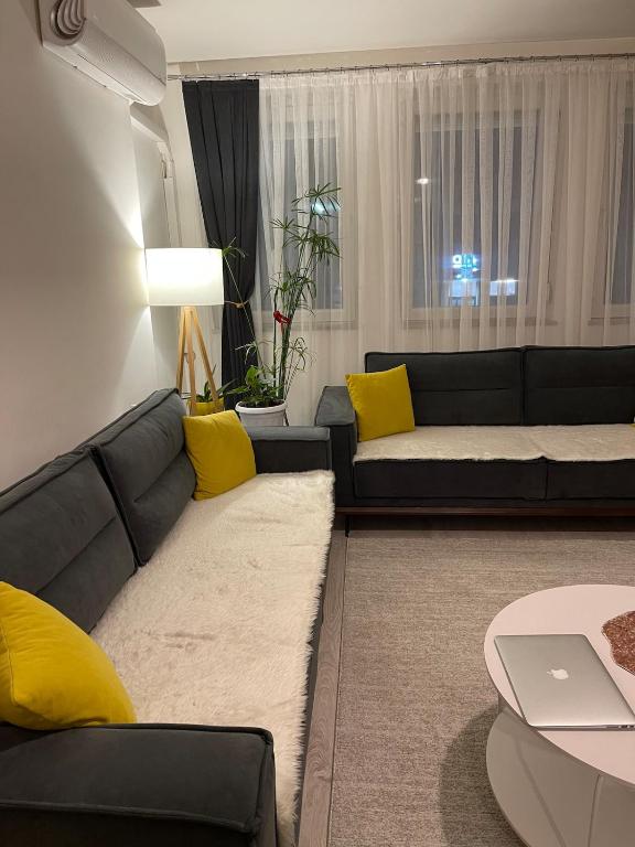 a living room with a black couch and yellow pillows at Flat in Fushë Kosova in Kosovo Polje