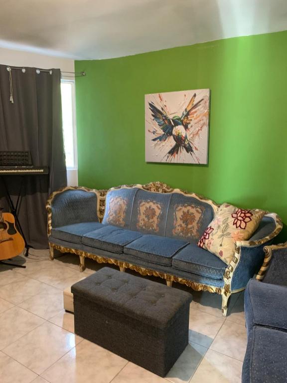 a living room with a blue couch and a green wall at Apartamento la 20 in Tijuana