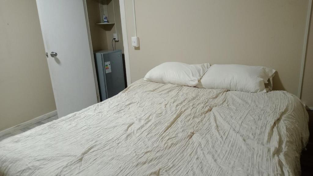 Una cama blanca con dos almohadas encima. en Cabaña en Valdivia, Chile, en Valdivia