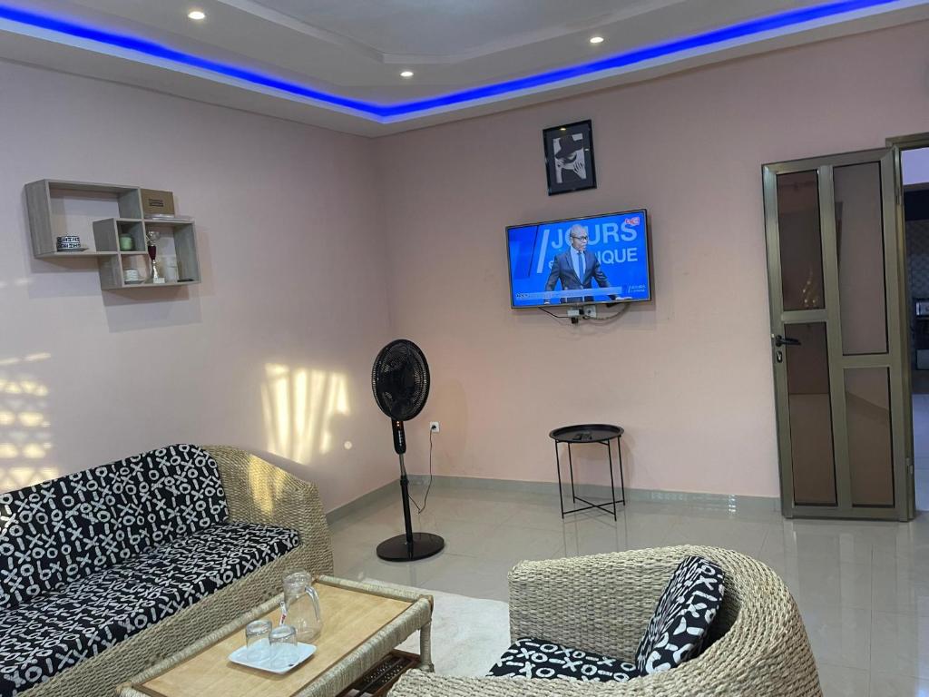 a living room with a couch and a tv on a wall at Résidence saint-Gall-H in Ouidah