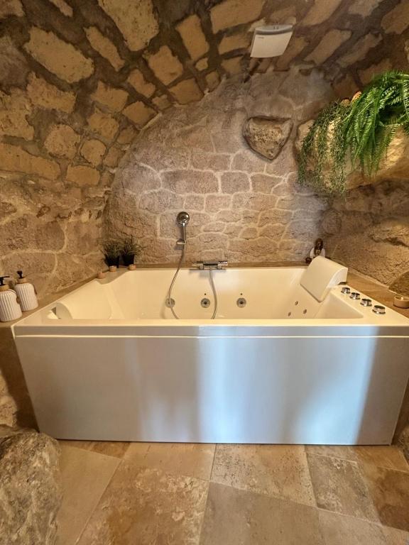 a bath tub in a room with a stone wall at Parenthèse entre forêt et château in Pierrefonds