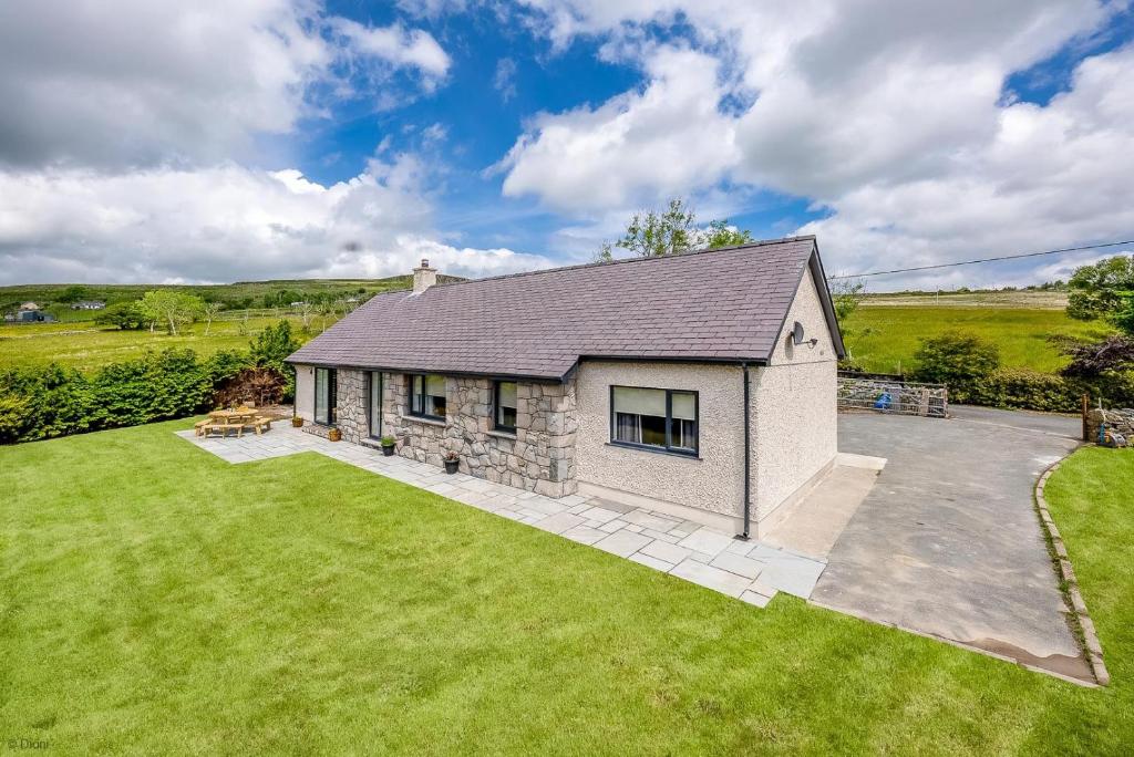 a stone house with a large yard at Adwyr-Mynydd in Dinorwic