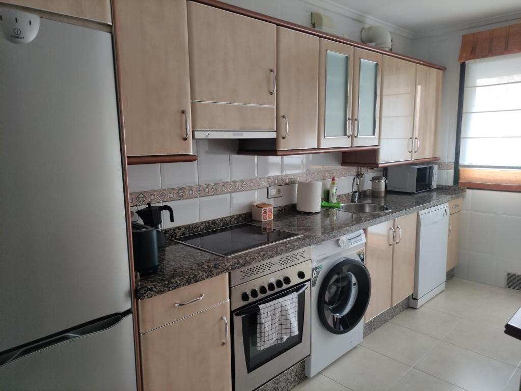a kitchen with wooden cabinets and a washer and dryer at El encanto del Texu in Pola de Lena