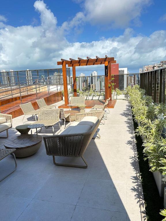 a patio with chairs and a gazebo on a roof at Melhores Flats - Elegante a 5 min do mar de Tambaú in João Pessoa