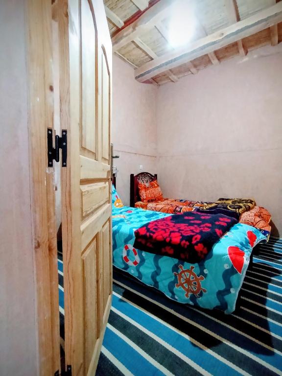 a room with two beds in it with a door at Auberge le calme restaurante in Bou Drarar