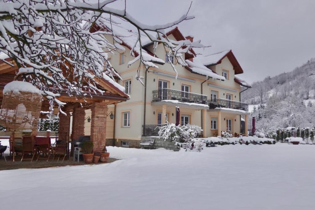una grande casa con la neve sui rami di un albero di Gorczańskie Apartamenty Papiernia - Noclegi w górach Gorce a Niedźwiedź