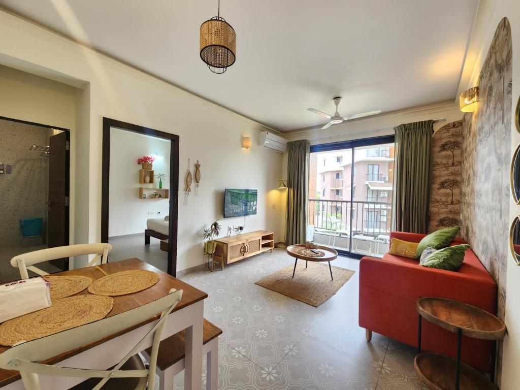 Premium 1BHK Beachside Apartment - Pool, Full Kitchen & Balcony, Candolim في كاندوليم: غرفة معيشة مع أريكة حمراء وطاولة