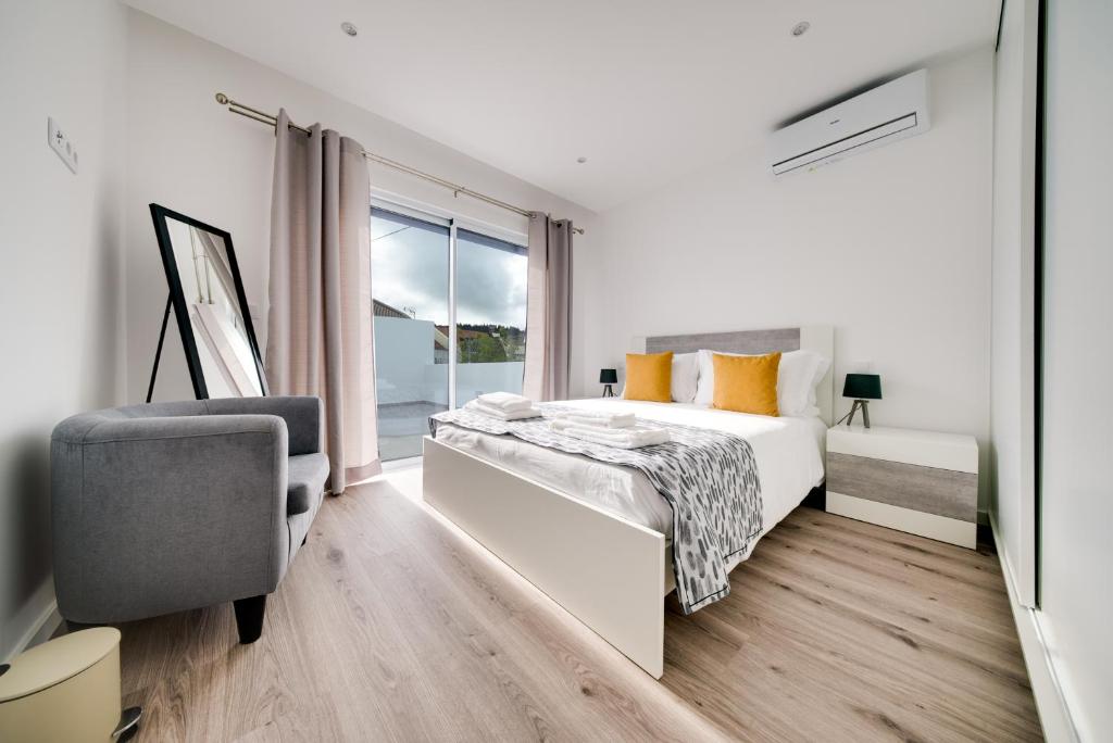 een slaapkamer met een bed, een stoel en een raam bij C&A Guest House in Furnas