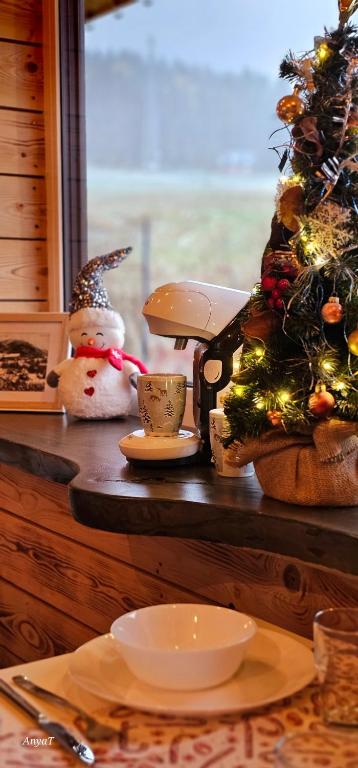 een tafel met een kerstboom, een sneeuwpop en bekers bij 3 Peaks Houses - Domki Całoroczne in Sokołowsko