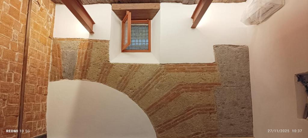 een zolderkamer met een raam en een bakstenen muur bij Teo a Toledo in Napels
