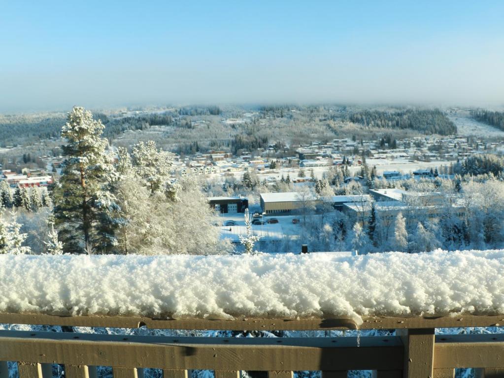 a fence covered in snow with a city in the background at Trysil turistesenter hytte in Trysil