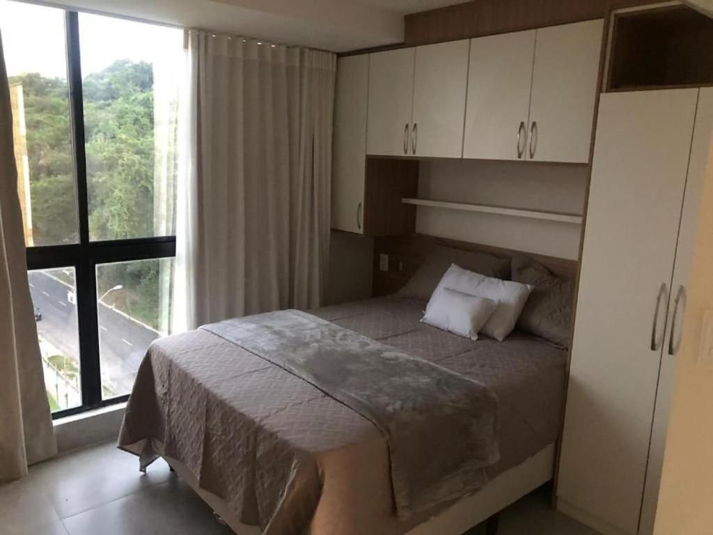 Un dormitorio con una cama y una ventana grande. en Melhores Flats - Único, pertinho do mar, en João Pessoa