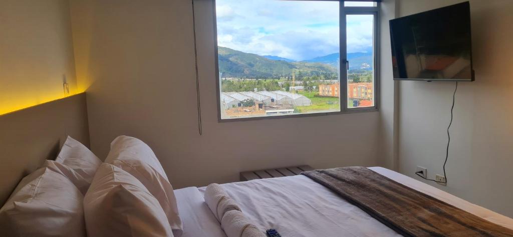 a bedroom with a bed and a large window at Posada Pa'sumerce in Tibasosa