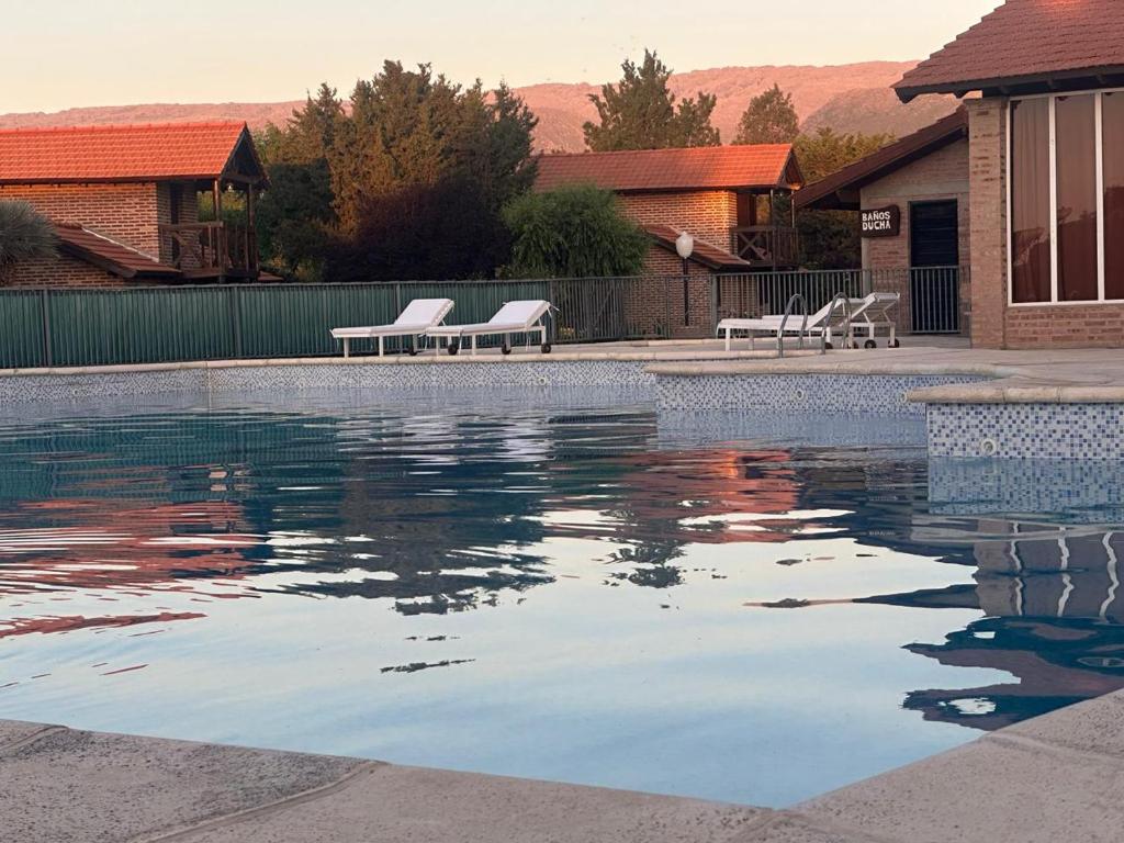 una piscina con due sedie e un po' d'acqua di Cabañas Costa Alta a Mina Clavero