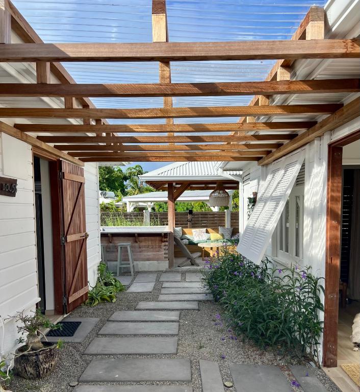 a pergola on a house with a patio at Les Cabanes cosy à 2 pas du lagon - charme et confort in Le François