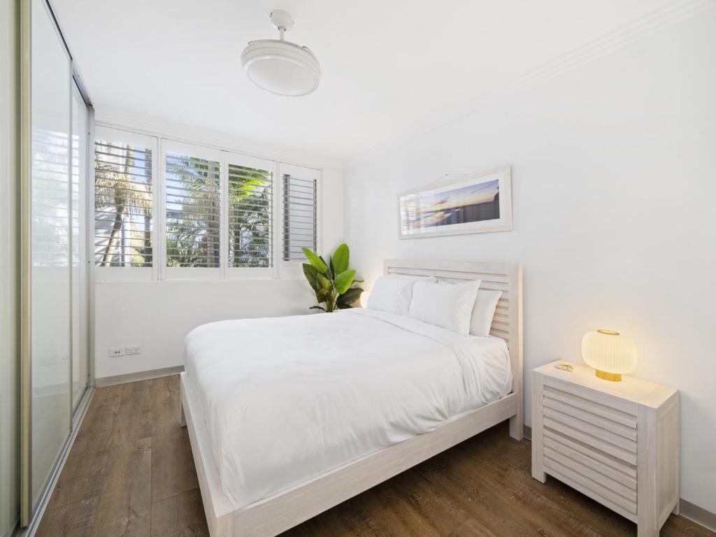 a white bedroom with a white bed and windows at Bright 2-Bed Apartment Near Narrabeen Beach in Narrabeen