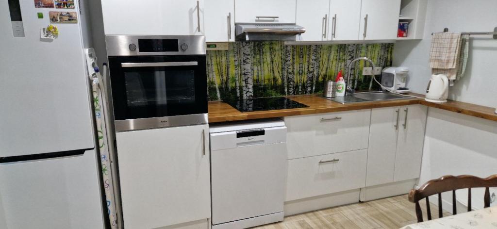 a kitchen with white cabinets and a refrigerator at Apartament in Rybnik