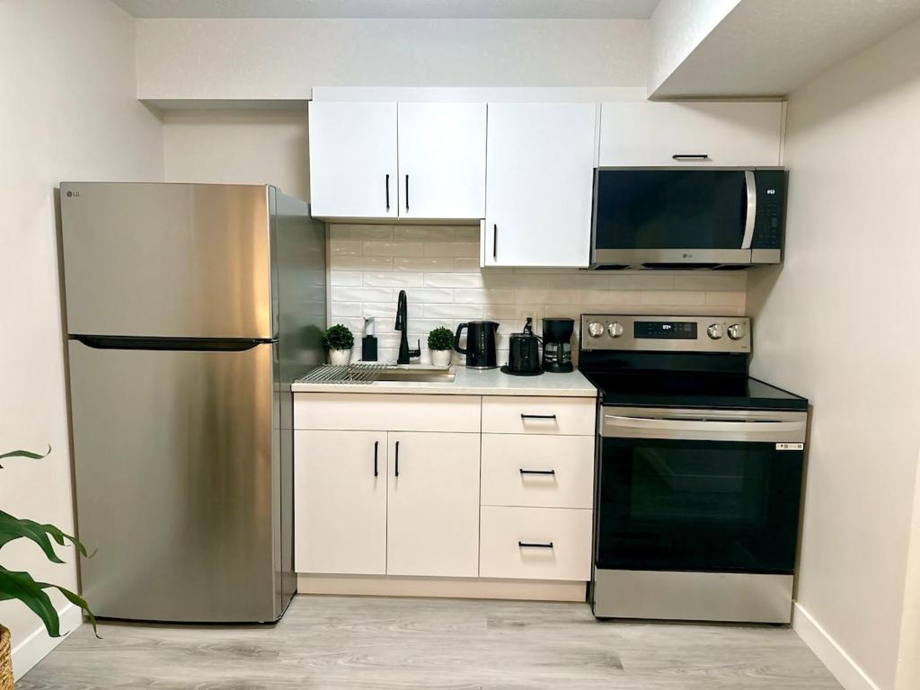 een keuken met witte kasten en een roestvrijstalen koelkast bij Cozy guest house in Regina