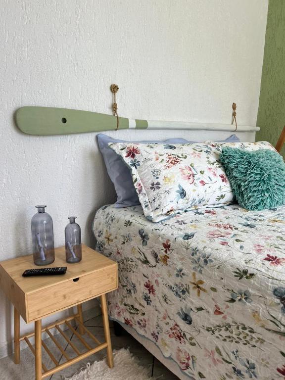 a bed with a surfboard on the wall next to a table at Sobradinho da Lagoa in Niterói