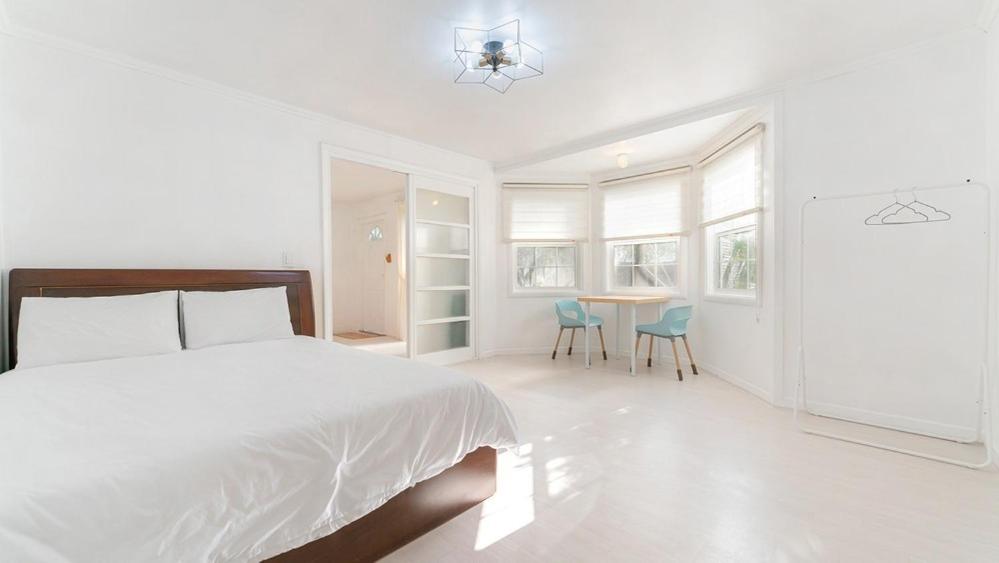 a white bedroom with a bed and a table and chairs at Taean Dokchae Trudy Pension in Taean