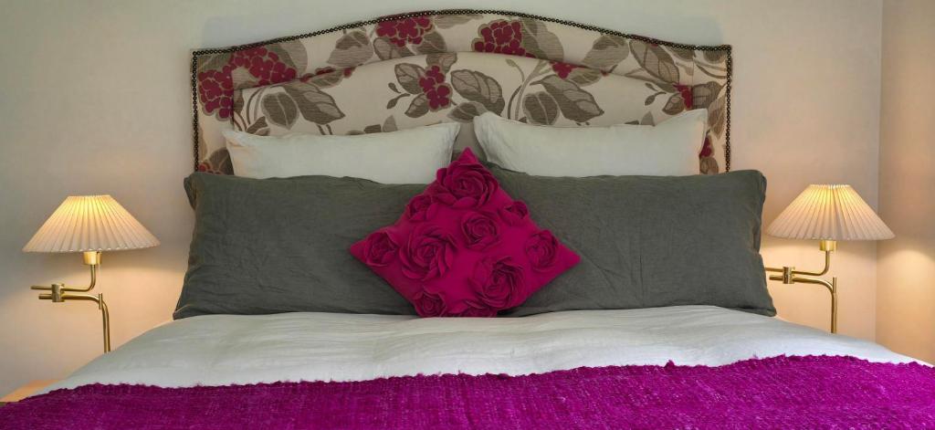 a bed with a pink pillow and two lamps at Chestnut Bay Country Retreat in Whakamarama