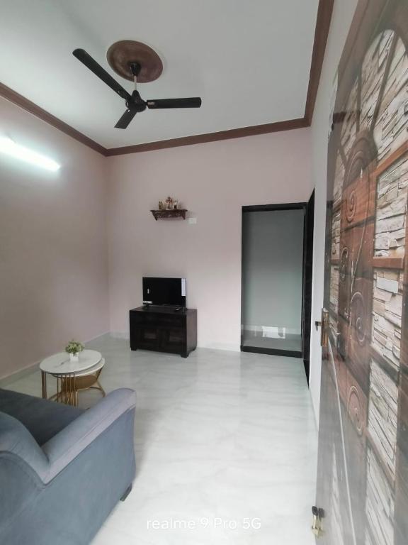 a living room with a couch and a ceiling fan at Ferns home stay in Betalbatim
