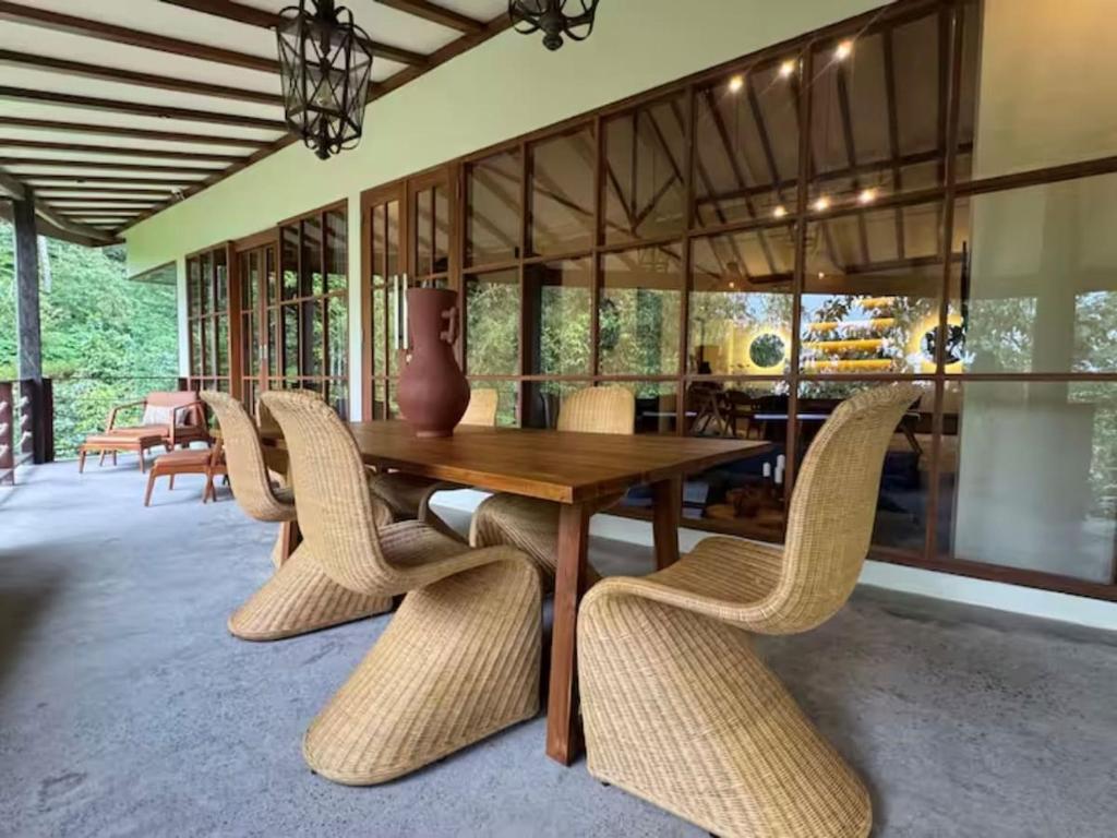 a dining room with a wooden table and wicker chairs at Mountain Villa & Nature Retreat - Fleur de Vie in Bedugul