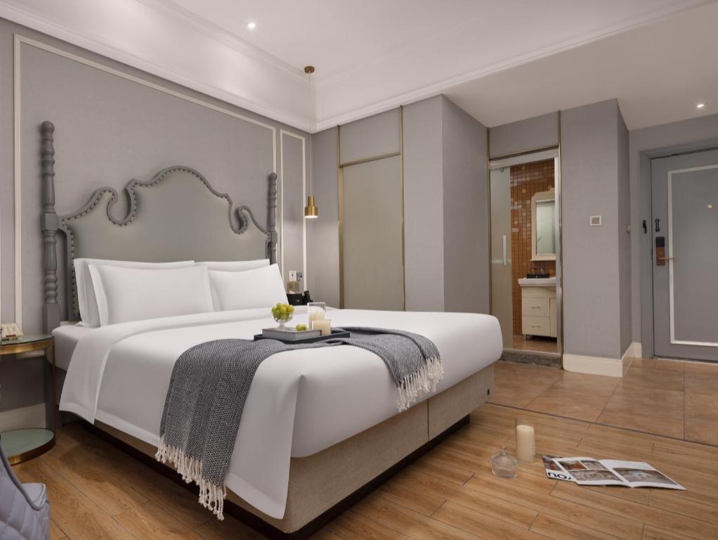 a bedroom with a large white bed with a table at Meisu Huanzhi Hotel Changsha Wuyi Square Hunan Museum Branch in Changsha