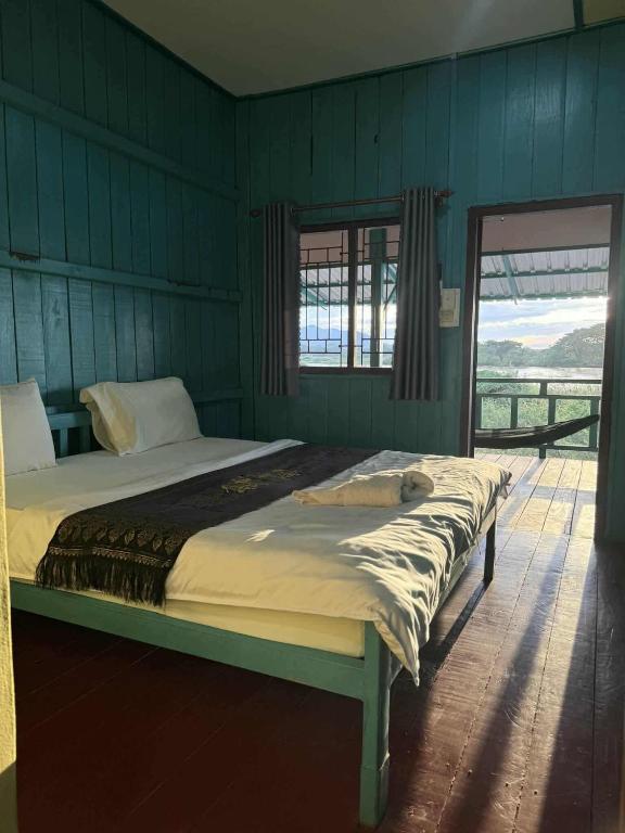 a large bed in a bedroom with green walls at Sompong Sunset View Guesthouse in Don Det