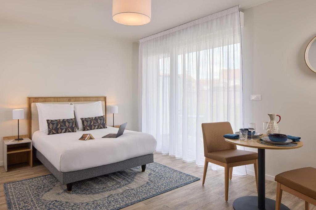 a bedroom with a bed and a table and a chair at Quality Suites Cholet in Cholet