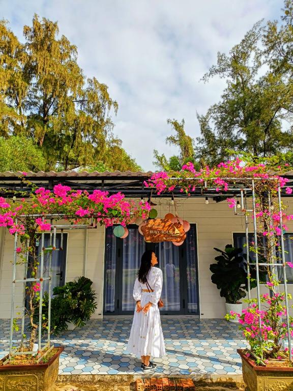 a woman standing in front of a house with pink flowers at Ruby House beachfront Đồi Dương La Gi in Lagi