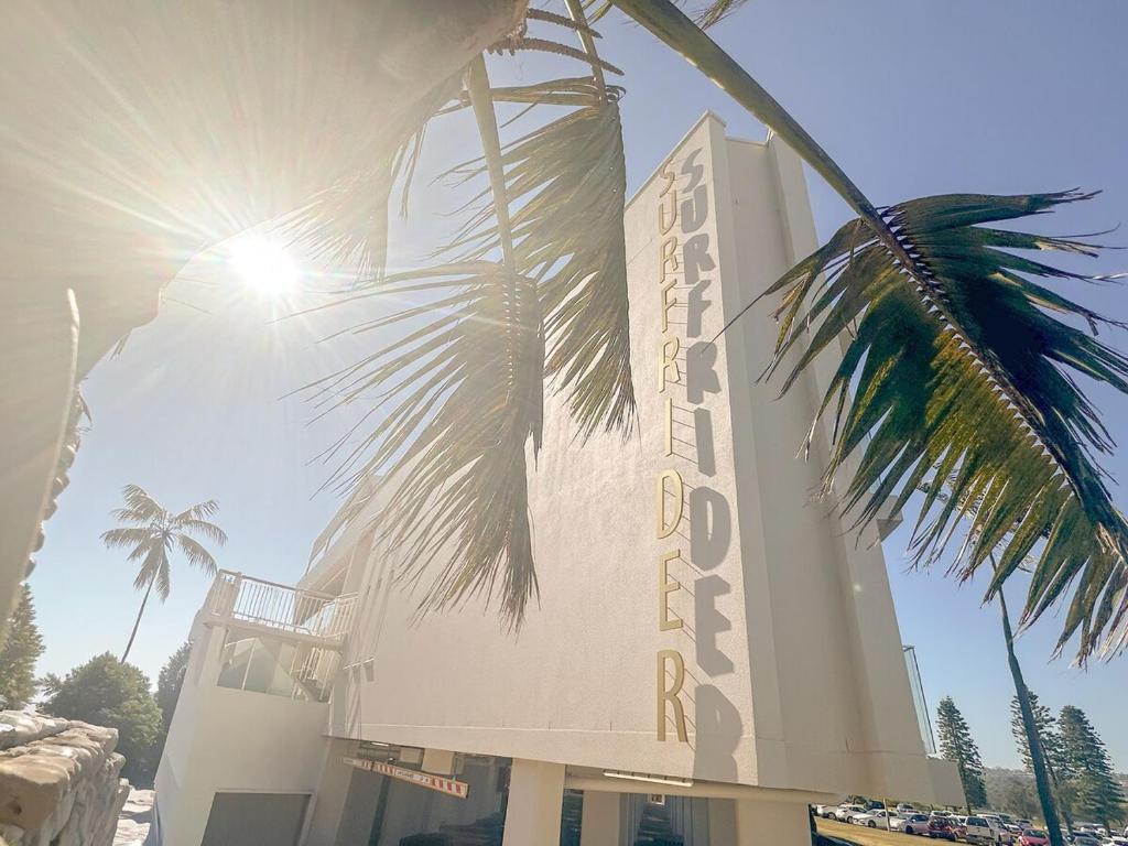 a building with a palm tree in front of it at 150m to Dee Why Beach in Deewhy