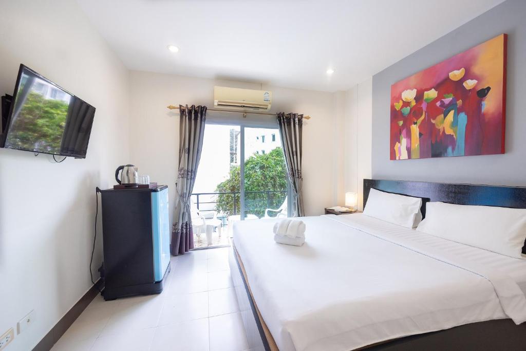 una camera da letto con un grande letto bianco e una finestra di Baan Yuyen Karon Guesthouse a Karon Beach