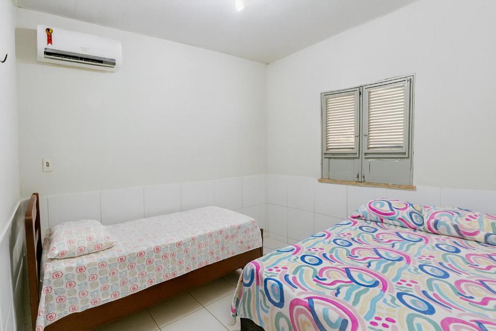 um pequeno quarto com uma cama e uma janela em Casa de Temporadas Alto Bonito em Luis Correia