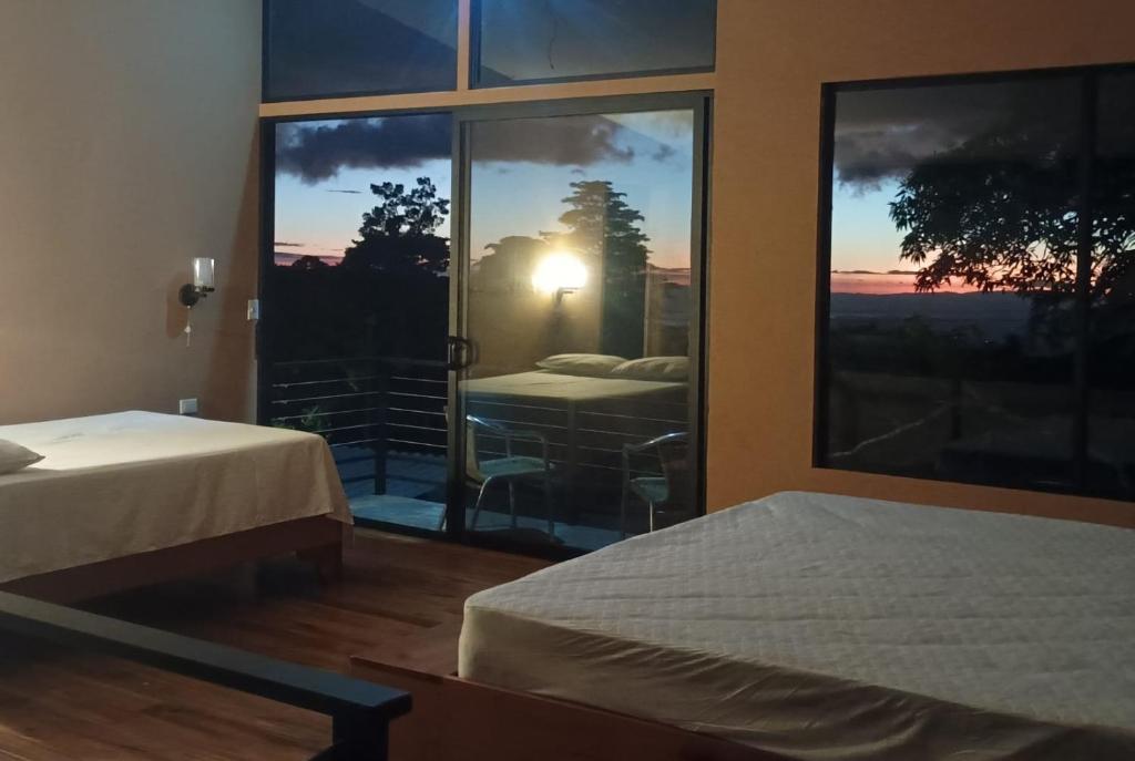 Tamara Monteverde View and Forest Chalet في مونتيفيردي كوستاريكا: غرفة بسريرين ونافذة كبيرة