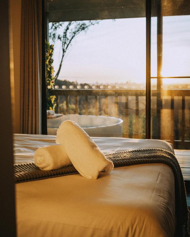 a bed with a towel on it with a window at Nebesa Tree top villas in Mudgeeraba