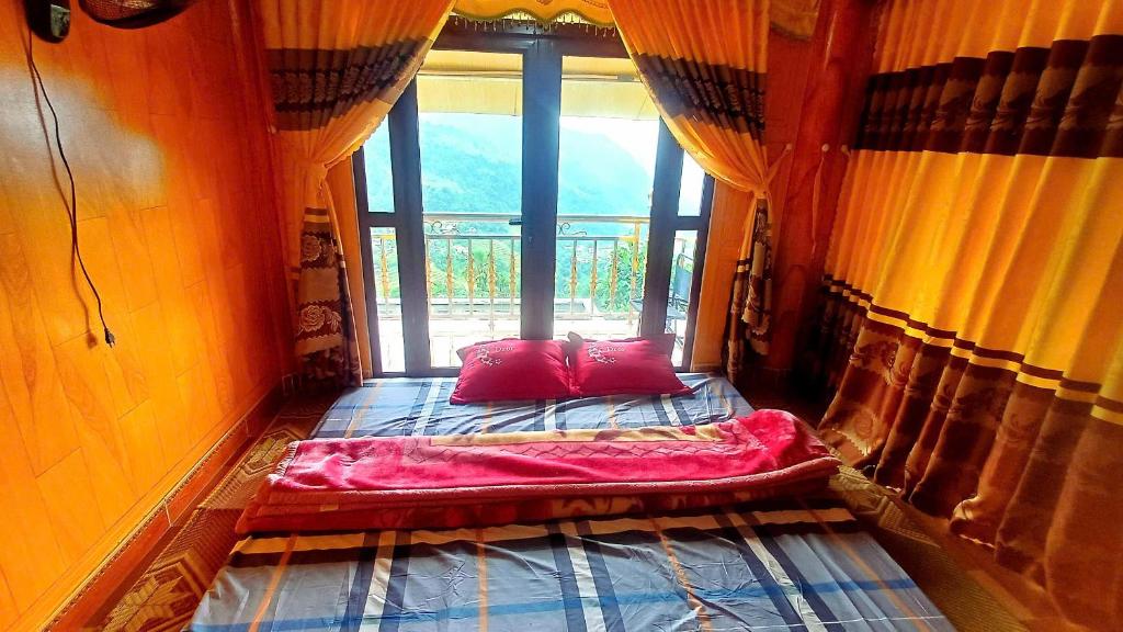 a bed with two red pillows in a room with a window at Homestay Quyền Linh-Tour Tây Côn Lĩnh in Kon Rung (1)