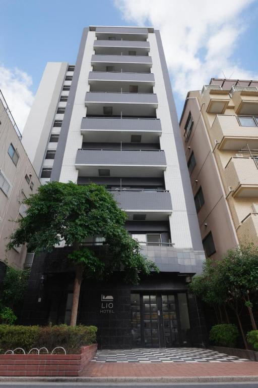 a tall white building with a tree in front of it at LIO HOTEL Tokyo Nippori in Tokyo